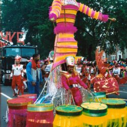 Giant colorful puppet and drummers in parade