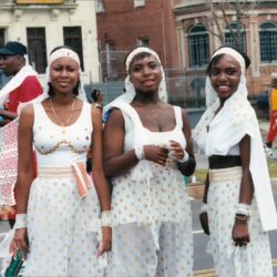 Three women in white dresses with headscarves