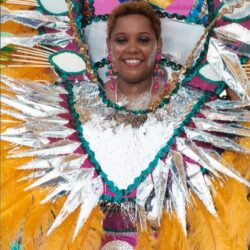 Smiling person in colorful feathered carnival costume