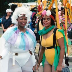 Two women in colorful carnival costumes with ribbons