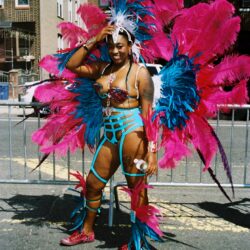 Smiling carnival performer in pink and blue feathers