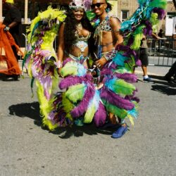 Two performers in vibrant feathered carnival costumes