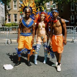 Three people wearing vibrant carnival costumes