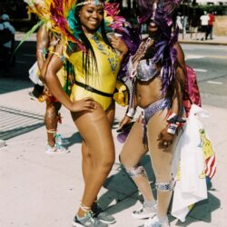 Two women in colorful carnival costumes on sidewalk