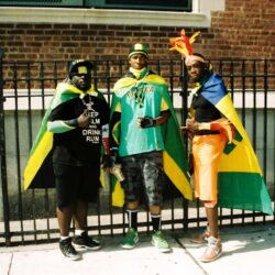 Three men wearing Jamaican flag capes