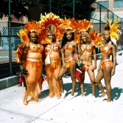 Five women in orange feathered carnival parade costumes