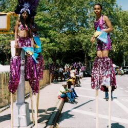 Two women on stilts in purple parade costumes