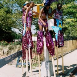 Three stilt walkers in purple sequined carnival costumes