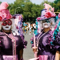Two masked performers in elaborate purple costumes