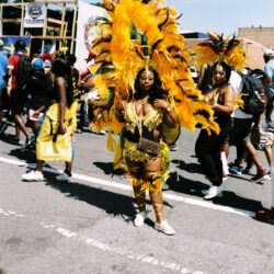 Dancer in yellow feathered costume at street parade