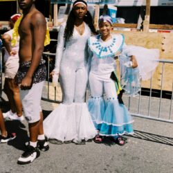 Three people in white and blue carnival costumes