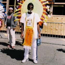 Man wearing large colorful feathered carnival headdress