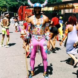 Performer in colorful horned carnival costume holding staff