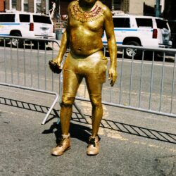 Gold painted street performer wearing sunglasses