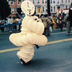Performer in round beige layered parade costume