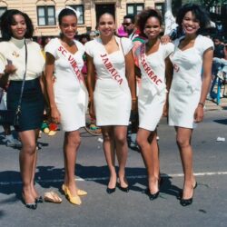 Five women wearing sashes at street parade