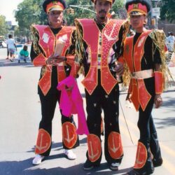 Three performers in red and gold carnival costumes