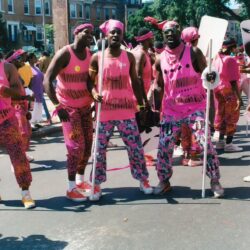 Parade performers in pink costumes and canes