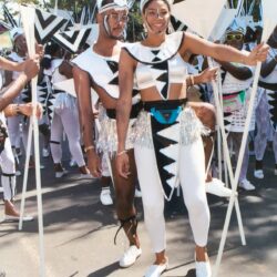 Smiling dancers in white geometric carnival costumes