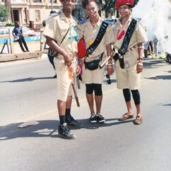 Three people in beige uniforms and red berets