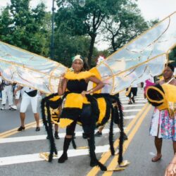 Parade participant wearing large bee costume wings