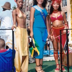 Three women in vibrant carnival costumes on float