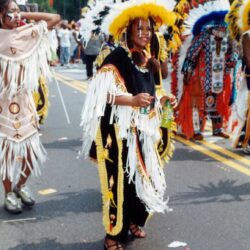 Parade participants wearing colorful feathered headdresses