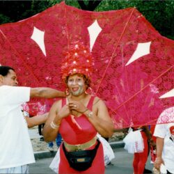 Smiling parade performer with large red fan