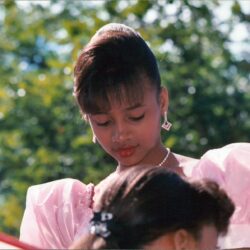 Young girl in pink dress outdoors looking down