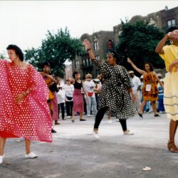 People dancing in colorful dresses on street