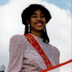 Smiling woman wearing pageant sash and gown