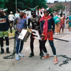 Men dressed as devils with chains at parade