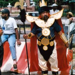 Carnival participant in gold costume with staff