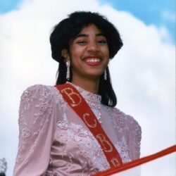 Smiling woman in pink beaded dress and sash