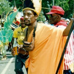 Parade participant in orange costume and headdress