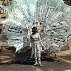 Person standing before large reflective silver sculpture