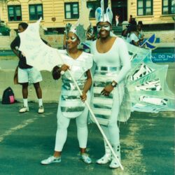 Two performers in silver parade costumes with flags
