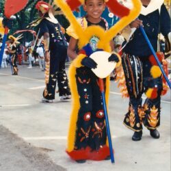Child in colorful feathered costume at parade