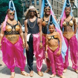 Five people in vibrant pink and gold costumes