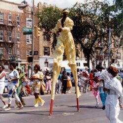 Stilt performer in yellow costume at parade