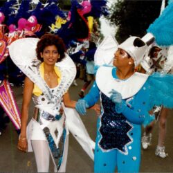 People in vibrant carnival costumes parading down street