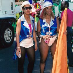 Two women in blue carnival costumes with flag