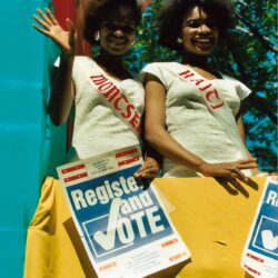 Two women in sashes holding Register and Vote
