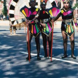 Three performers in vibrant carnival parade costumes
