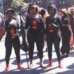Three people in black costumes with red stars