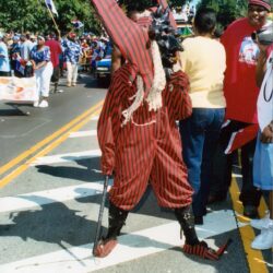 Person in red striped jester costume at parade