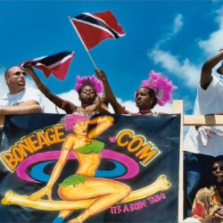 People on carnival float waving Trinidadian flags
