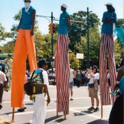 Parade stilt walkers in colorful tall pants
