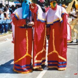 Three masked performers in bright red parade costumes