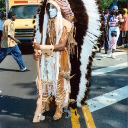 Person in feathered headdress marching in parade